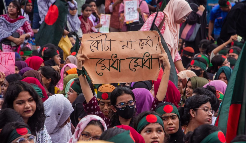 Demonstrators during Bangladesh's 2024 quota reform movement—students in national colours; placards include Bengali messaging on quota and merit.